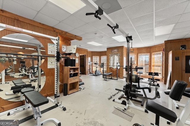 workout area with wood walls and a drop ceiling