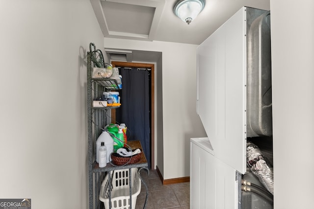 clothes washing area featuring light tile patterned floors, laundry area, stacked washer and clothes dryer, and baseboards