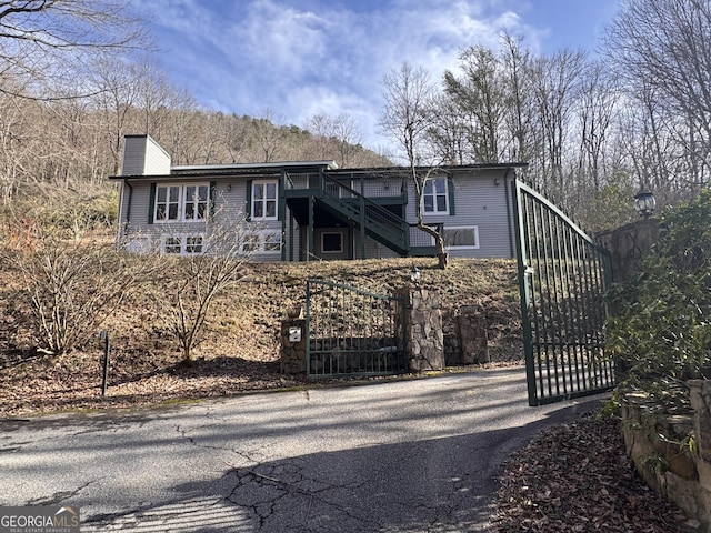 view of front of home with a gate, fence, a chimney, and stairs