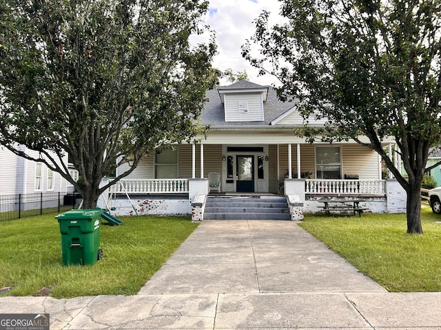 view of front facade with a porch, roof with shingles, fence, and a front lawn