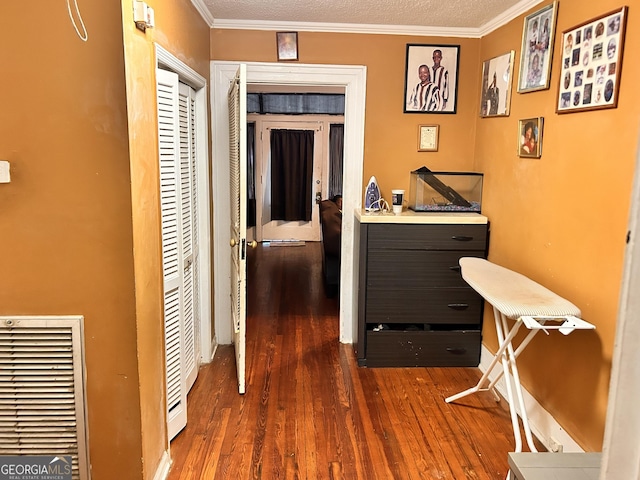 hall featuring a textured ceiling, dark wood-type flooring, visible vents, and crown molding