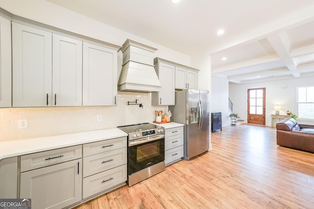 kitchen with appliances with stainless steel finishes, decorative backsplash, light wood-style floors, and custom range hood