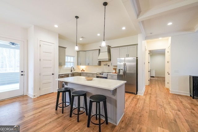 kitchen featuring light wood finished floors, appliances with stainless steel finishes, a breakfast bar area, and gray cabinetry