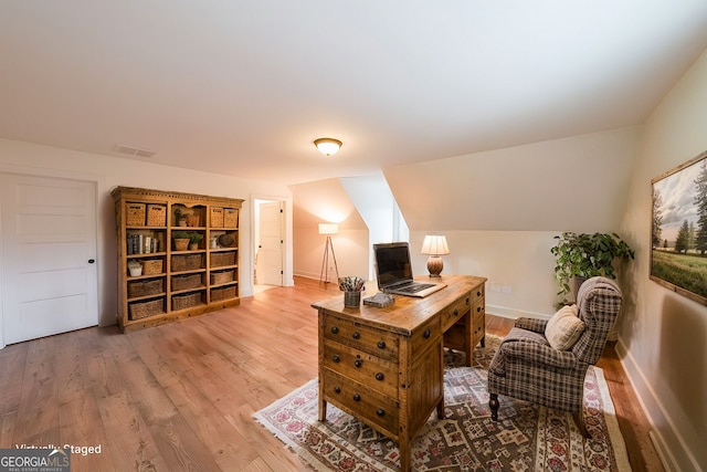 home office with vaulted ceiling, baseboards, visible vents, and light wood-style floors