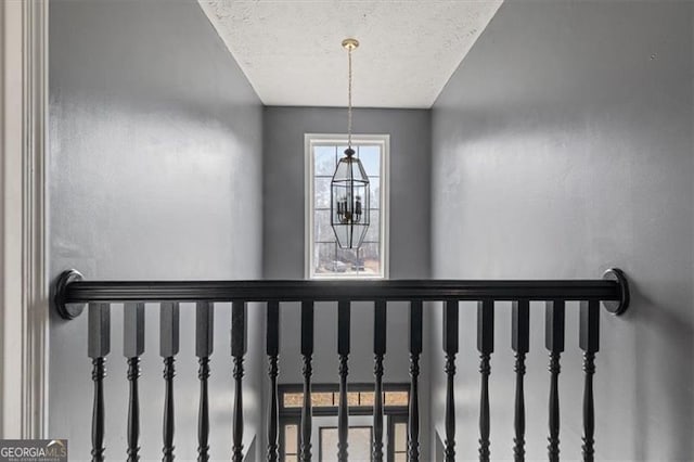 staircase with a notable chandelier and a textured ceiling