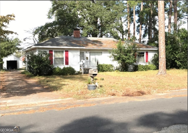 view of front of house with dirt driveway, a chimney, and a detached garage