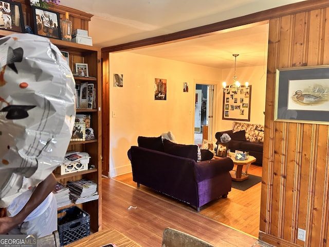 living room with a chandelier, wood walls, and wood finished floors