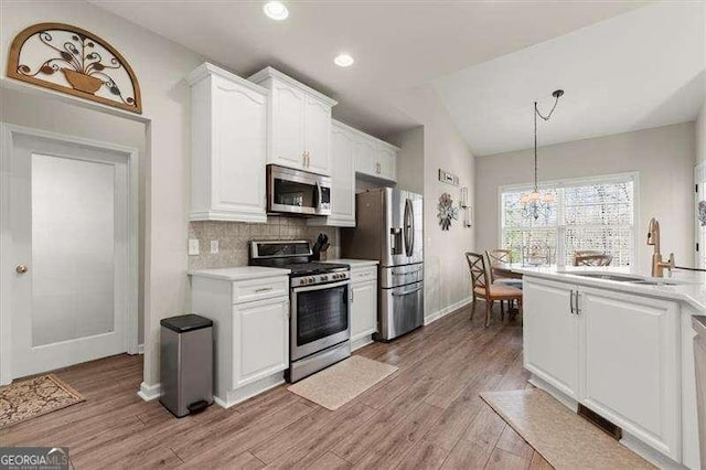 kitchen with stainless steel appliances, a sink, white cabinets, light countertops, and backsplash