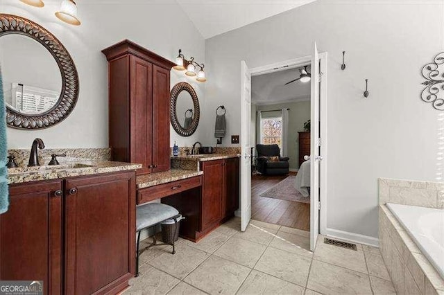 ensuite bathroom featuring connected bathroom, a relaxing tiled tub, visible vents, vanity, and tile patterned floors