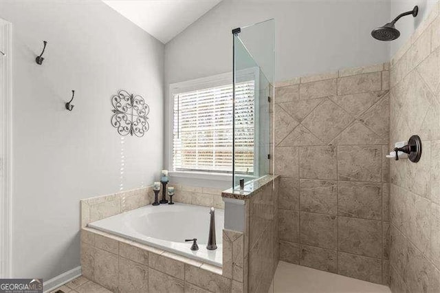 bathroom featuring a bath, vaulted ceiling, and tiled shower