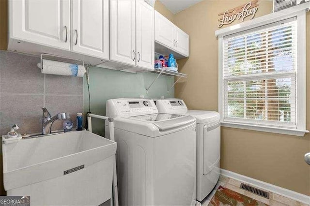 clothes washing area featuring cabinet space, baseboards, visible vents, washer and clothes dryer, and a sink