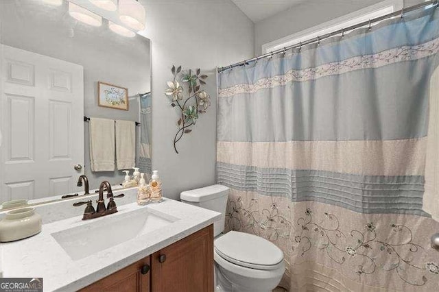 bathroom with toilet, curtained shower, and vanity