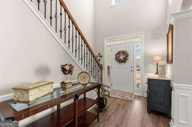 entrance foyer with a high ceiling, stairway, and wood finished floors