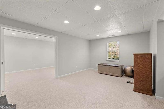 below grade area with a paneled ceiling, carpet flooring, baseboards, and recessed lighting