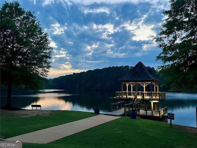 view of dock with a water view and a lawn