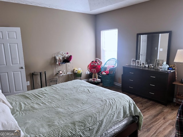 bedroom with a textured ceiling and wood finished floors