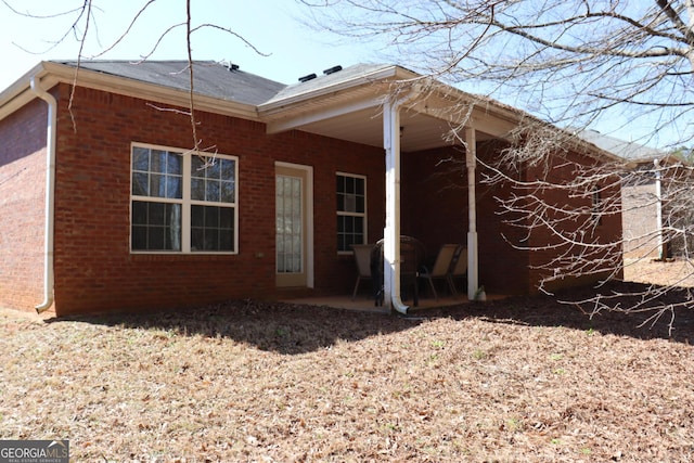 back of property with brick siding and a patio