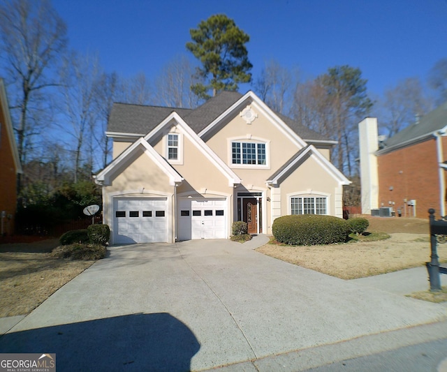 traditional-style house with a garage, central AC unit, concrete driveway, and stucco siding