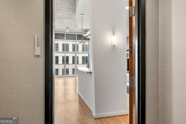 corridor with light wood-type flooring and baseboards