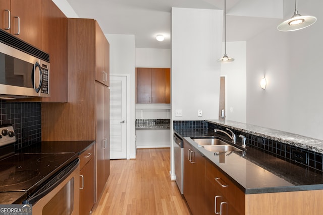 943 Peachtree St NE Unit 2009, Atlanta, GA 30309 - kitchen featuring appliances with stainless steel finishes, brown cabinetry, a sink, and decorative light fixtures