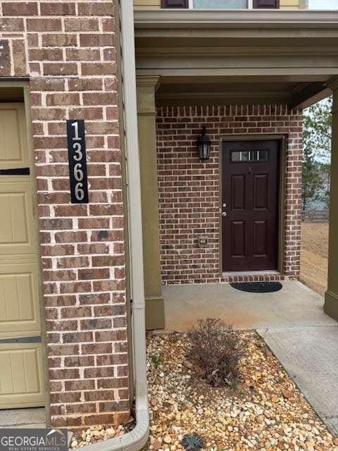 view of exterior entry featuring brick siding and an attached garage