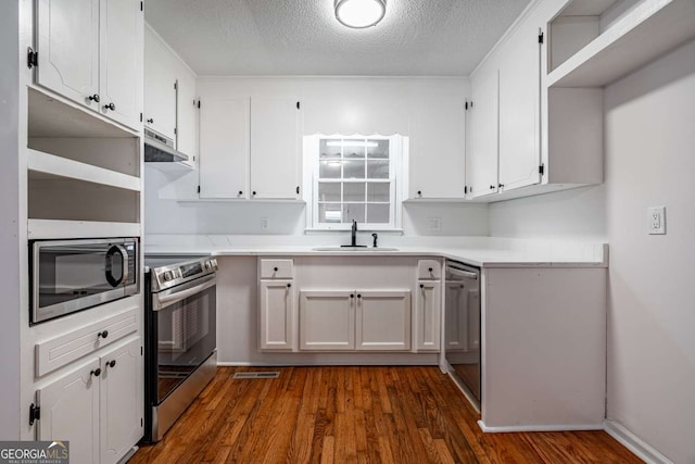 kitchen featuring open shelves, light countertops, appliances with stainless steel finishes, white cabinetry, and a sink