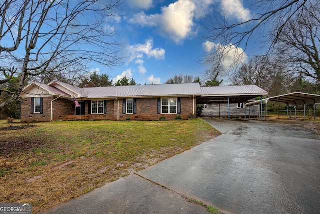 ranch-style home with metal roof, brick siding, driveway, a carport, and a front lawn