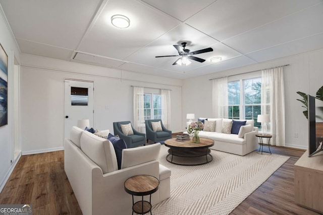 living area with dark wood-style floors, a ceiling fan, and baseboards