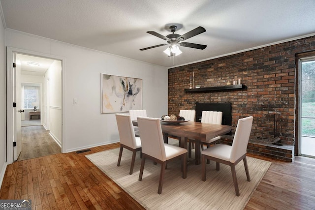 dining room featuring a textured ceiling, light wood-style flooring, visible vents, ornamental molding, and a wealth of natural light