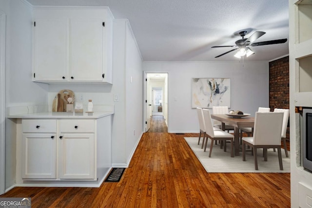 unfurnished dining area with ceiling fan, baseboards, dark wood finished floors, and a textured ceiling