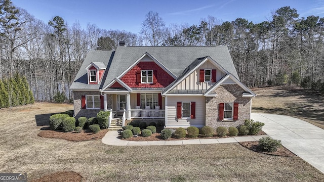 craftsman-style house with driveway, a porch, board and batten siding, and brick siding