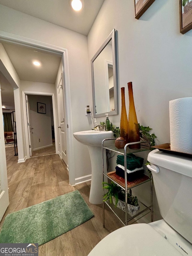 hall featuring light wood finished floors, baseboards, and a sink