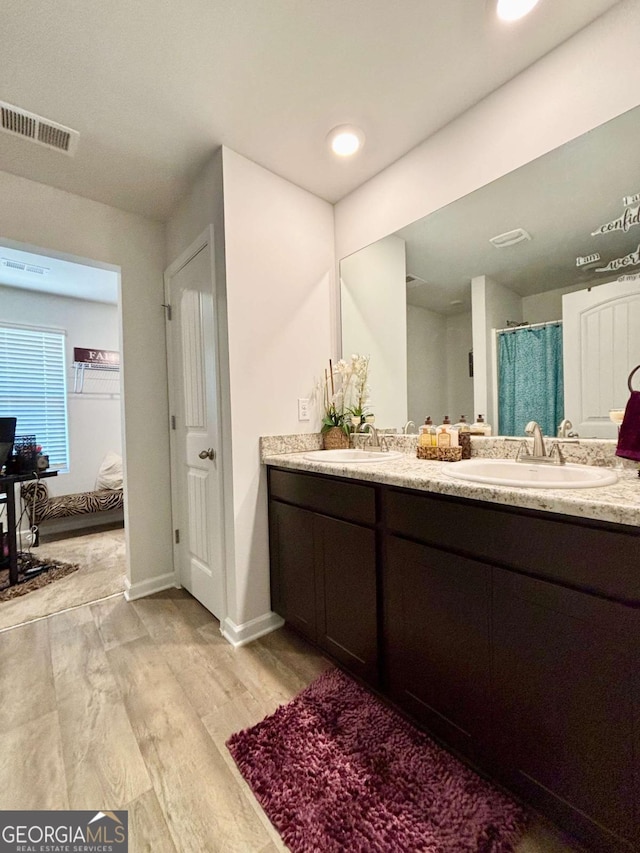 bathroom featuring double vanity, wood finished floors, a sink, and visible vents