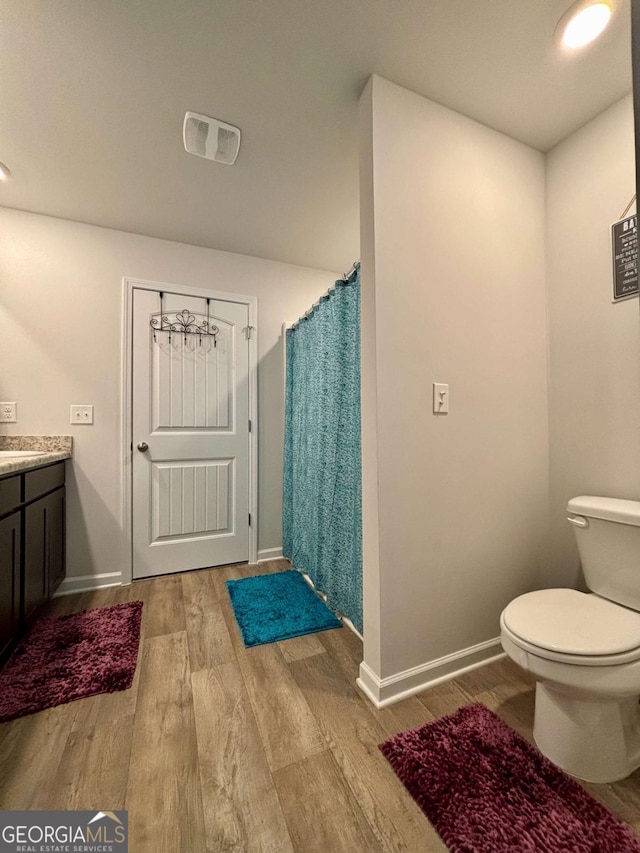 full bathroom featuring visible vents, toilet, vanity, wood finished floors, and baseboards