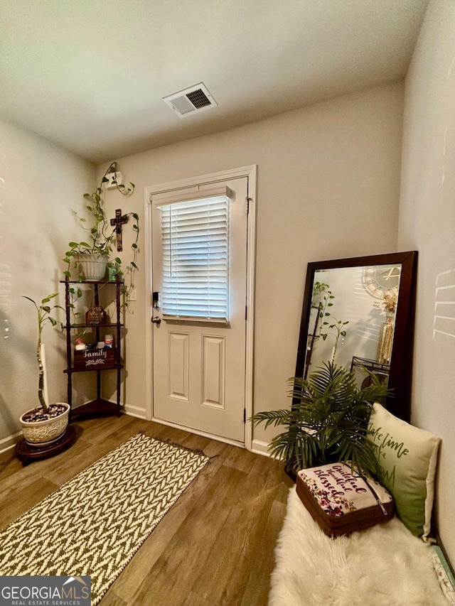 doorway with wood finished floors, visible vents, and baseboards