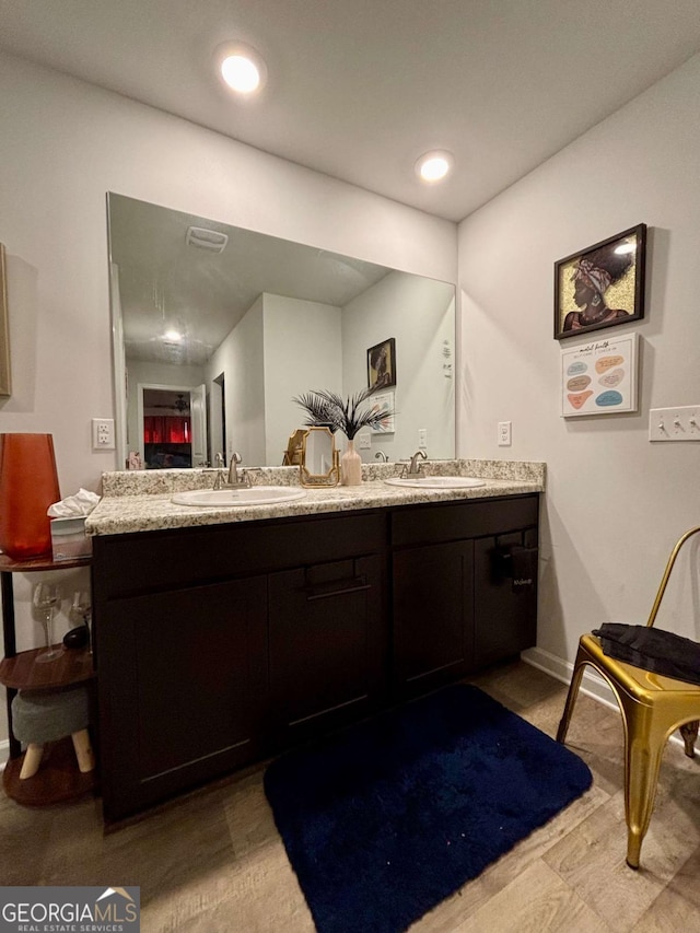 full bath with baseboards, double vanity, a sink, and recessed lighting