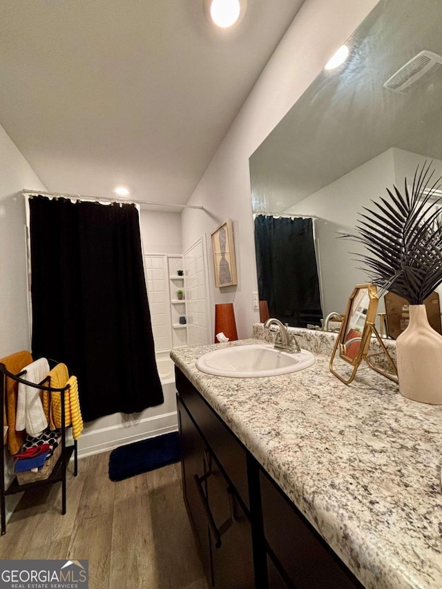 full bath with visible vents, wood finished floors, vanity, and shower / bathtub combination with curtain