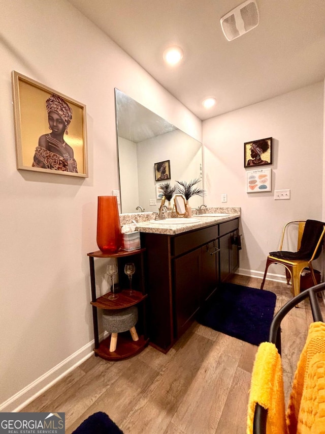 bathroom with a sink, baseboards, visible vents, and wood finished floors