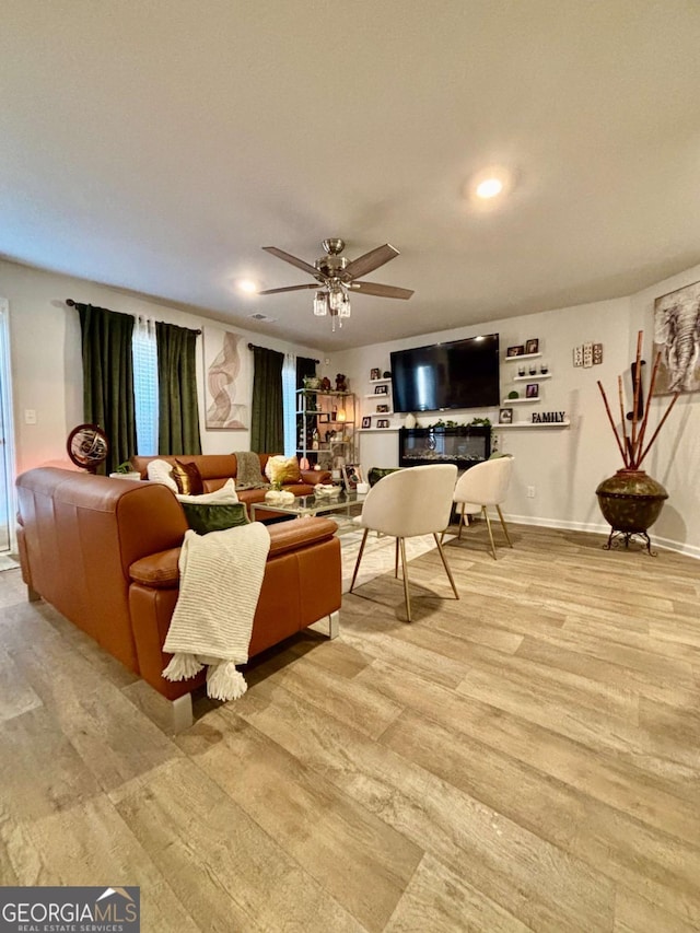 living room featuring light wood-style floors, baseboards, a ceiling fan, and recessed lighting