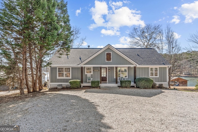 view of front of home with board and batten siding, covered porch, and roof with shingles