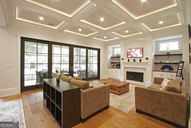 living area with french doors, a fireplace, light wood-style floors, and a healthy amount of sunlight