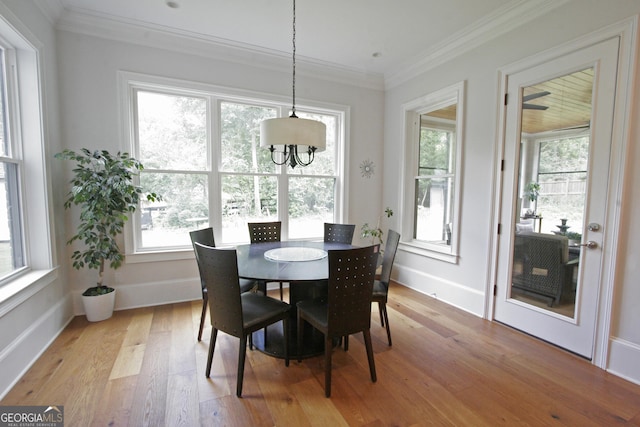 dining room featuring baseboards, crown molding, and light wood finished floors