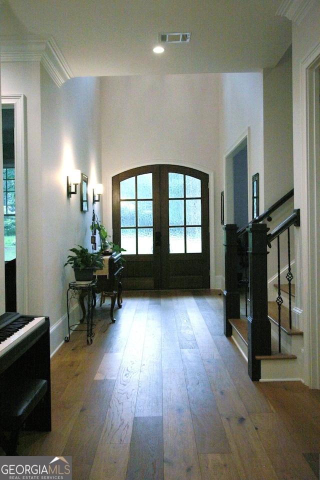 entrance foyer featuring arched walkways, french doors, visible vents, stairway, and hardwood / wood-style floors