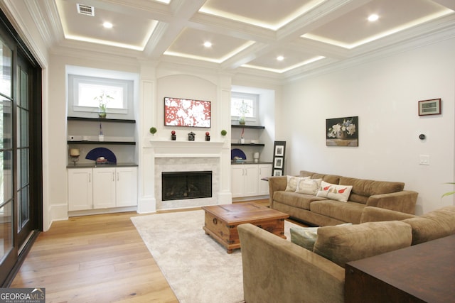 living area featuring coffered ceiling, visible vents, ornamental molding, light wood finished floors, and a tiled fireplace