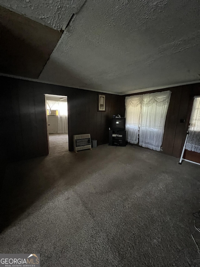 interior space with carpet floors, a textured ceiling, and heating unit