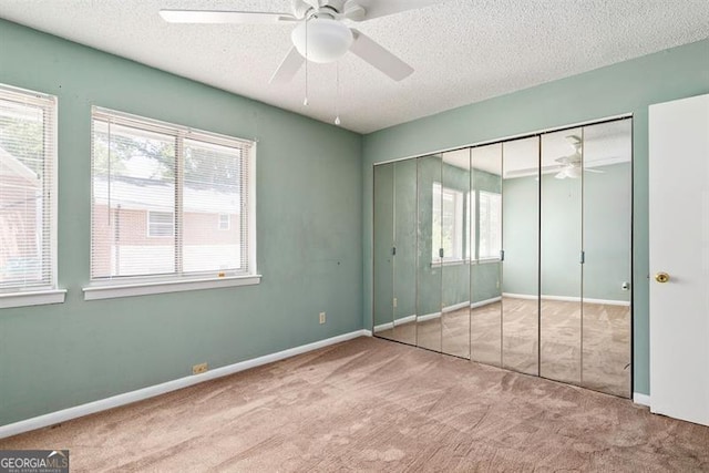 unfurnished bedroom featuring a closet, carpet, a ceiling fan, and a textured ceiling