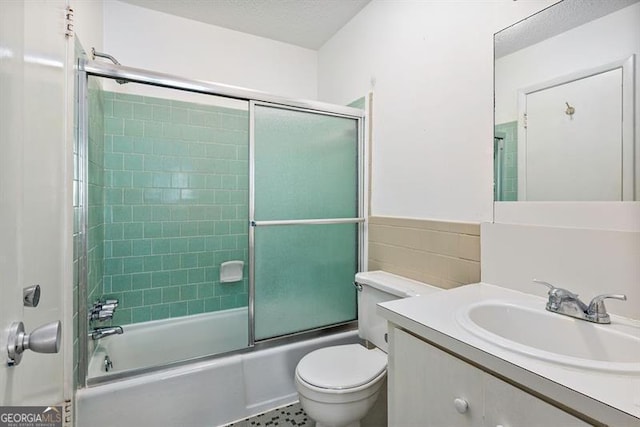 bathroom with combined bath / shower with glass door, toilet, a textured ceiling, and vanity