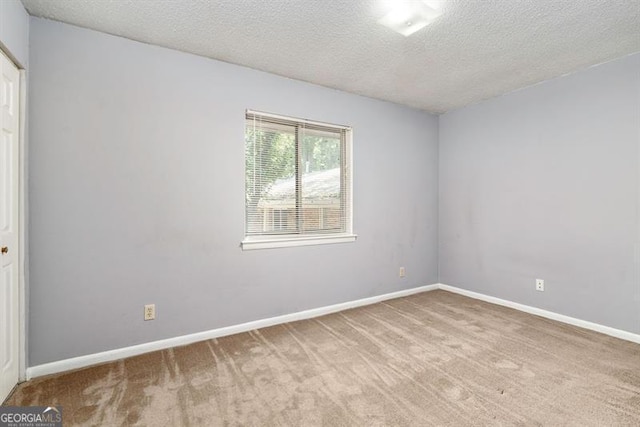 unfurnished room featuring light carpet, a textured ceiling, and baseboards