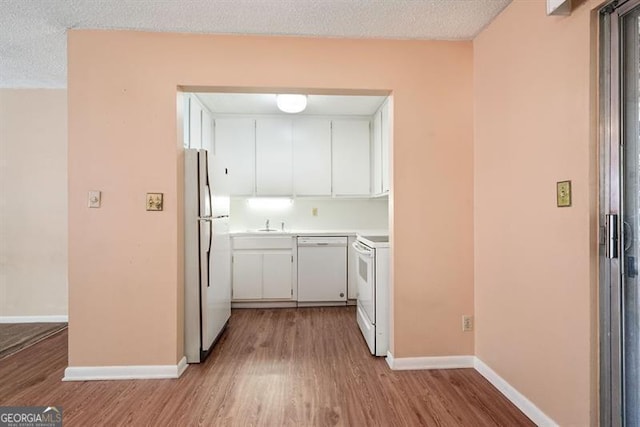 kitchen featuring white cabinetry, white appliances, wood finished floors, and baseboards