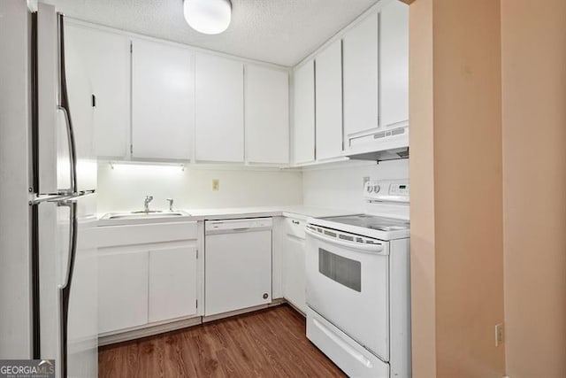 kitchen featuring white appliances, dark wood finished floors, a sink, under cabinet range hood, and white cabinetry